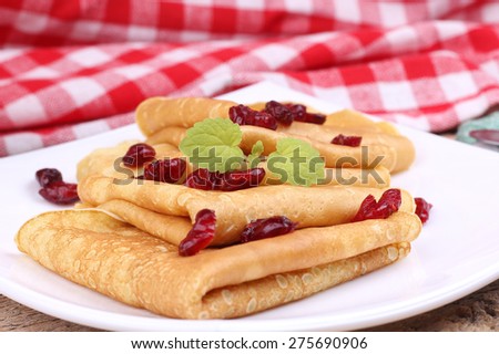 Dried berries and thin pancakes. Delicious Breakfast, lunch. To eat pancakes. A coffee shop, restaurant. Recipe pancakes. Closeup. Pancakes with mint and cranberries. Fried pancakes. Crepes for lunch.