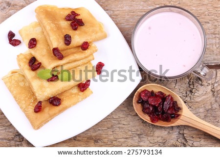 Hot delicious pancakes. Thin pancakes with berries. Cranberry. Dried berries. Yogurt and pancakes. Fried pancakes. The food on the table. Cup of yogurt, crepes and dried cranberries. Sweet pancakes.