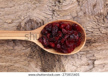 Wooden spoon with dried berries on the table. Dried cranberries on the table. The view from the top. Spoon with berries.