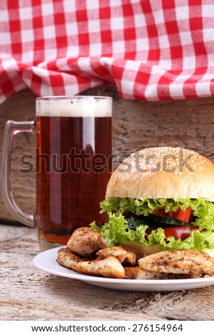 Glass of dark beer and Burger meat. Fried chicken meat. Food and Beer. Lettuce, cucumber, tomato, bread, meat and beer. An alcoholic drink. A plate with meat and Burger.