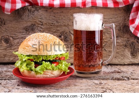Glass of dark beer and Vegetarian Burger. An alcoholic drink. A plate with Burger and glass of beer. Food and Beer. Lettuce, cucumber, tomato, bread and beer.