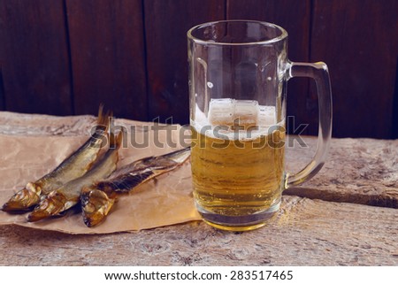 Unhealthy diet, alcoholism. A glass of beer and fish. Beer and snacks. Food and beverage. Appetite. An evening in the pub. Salty smoked fish and half-empty glass of light beer.