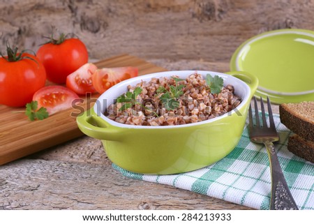 A plate of buckwheat and vegetables. Fork and a plate. In the kitchen, cooking, cooking school. Ripe tomatoes, buckwheat and bread. Diet. A delicious and hearty meal. Home-cooked food.