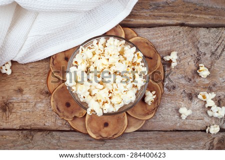 A bowl of popcorn on the table. Corn popcorn. Delicious movie snack. Mouth-watering classic appetizer. A lot of popcorn on the table. Top view. Napkin on the table.