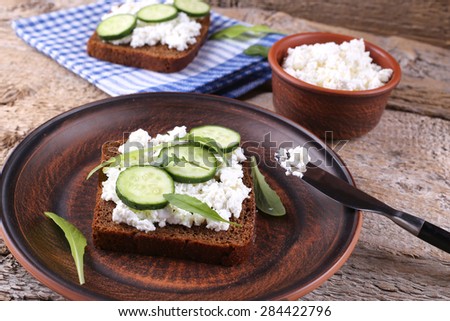 Sandwiches with ricotta on the table. The sandwich on the plate. Light lunch, snack. Cafeteria, restaurant, home-cooked food. A sandwich with cucumber and herbs.
