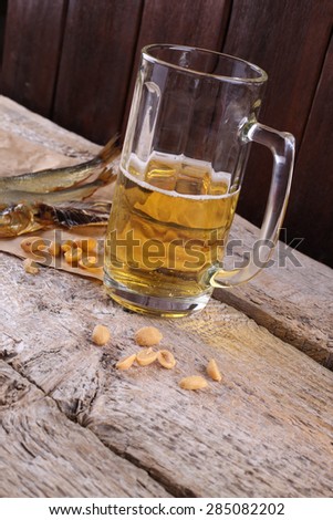 Glass of beer and fish. Beer and snacks. Food and drink. Unhealthy diet, alcoholism. Appetite. An evening in the pub. Salty smoked fish and half-empty glass of light beer.