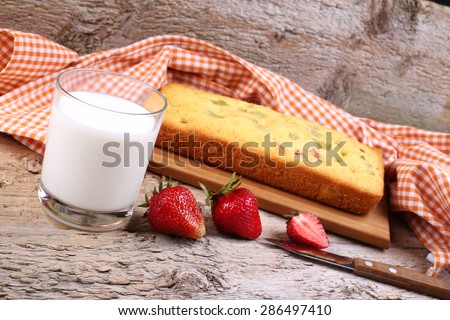 Rhubarb pie on the table. A glass of milk and a biscuit. Sponge cake with Apple, ripe strawberries and a glass of milk. Biscuit, beverage, knife, and berries. Home-like atmosphere.