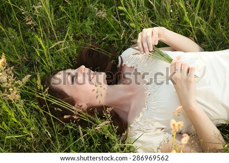 The girl in the field. Young woman lying in the grass. Smiling girl in grass. To relax in nature. Unity with nature. The forces of nature. Dreamy girl.