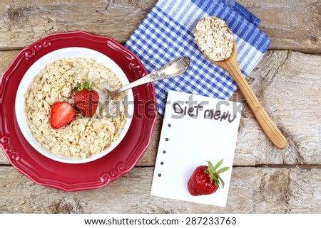 Porridge with strawberries. Oatmeal with strawberries. Oatmeal in a bowl. Spoon, a note, a plate of porridge. Diet menu. Weight loss, weight loss, diet concept.