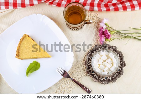 Slice of key lime pie on a plate. A delicious and appetizing dessert. Cakes, cheesecake. Sugar, refined sugar, a Cup of tea and a piece of cake. Pie with mint leaves. Carnation flowers on the table.