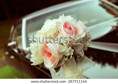 Black car with a delicate bouquet of roses. Wedding car decoration. A special day, wedding, holiday. A bouquet of artificial flowers. Floristry, decoration of the wedding.