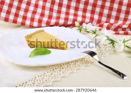 Portion of key lime pie on a platter. In the restaurant, in the cafeteria. Fork, a piece of cake, peppermint leaf. The tablecloth on the table. In the kitchen. In the restaurant, in the cafeteria.