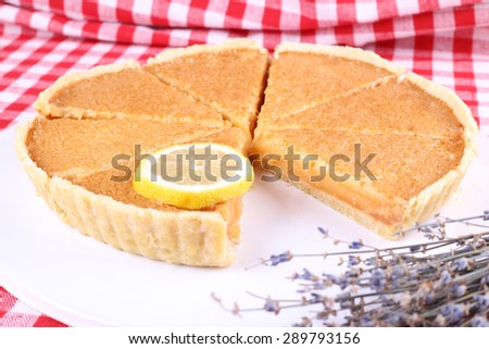 Round lemon cake, cut into slices. Delicious lemon cake. Pastries, patisserie, cafeteria. Pie and lemon. Dried lavender and pie on the table. Selective Focus.