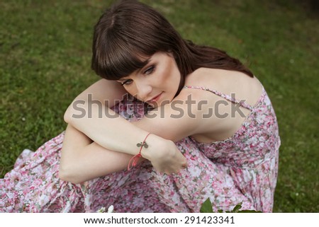 Beautiful sad girl. The girl in the park. Romantic look. Thinking, sadness, loneliness, depression. Girl sitting on the grass. Young woman in the park. Retro look. Dreaming girl. Young woman.