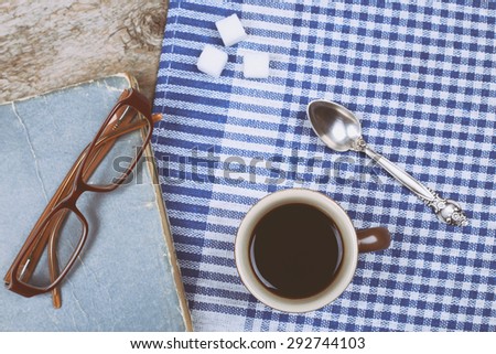 Old Book, Glasses, teaspoon, cup of strong coffee. Library, university, knowledge, information. Read books. The student, bookworm, literature. Tablecloth in small cells.