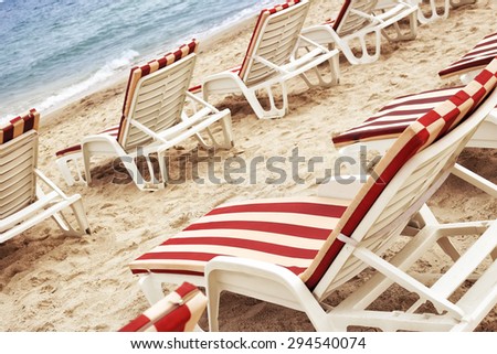 Lots of sun beds in a row on the coast. Folding chairs on the beach. Sandy beach and sun beds with mattresses. Ocean Beach. White sand and waves of the sea.
