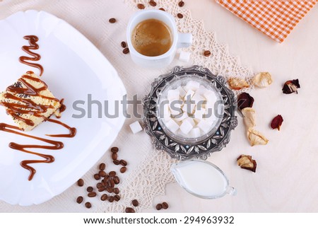 Cheesecake with caramel sauce. A cup of strong coffee, milk and piece of cheesecake dessert. Sugar, rose petals, coffee beans, cup of coffee and cake. Breakfast, lunch. Sweet food.