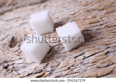 Three cubes of sugar. Refined sugar on the table. Cubes of sugar on the table. Sweet foods and sweets. Sugar on the wooden table. Subject macro shooting. Macro sugar.