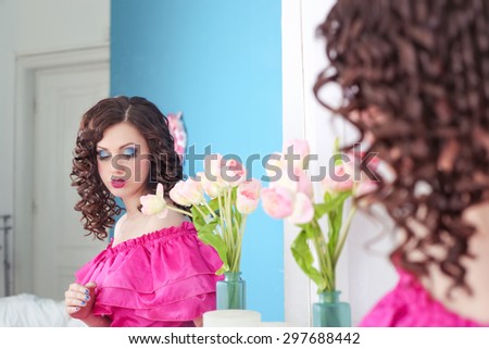 Beautiful girl in the image of the doll, the girl like a doll. The girl in the dressing room. Bright make-up. Girl doll with bright makeup. The girl in the mirror reflection. Prom.