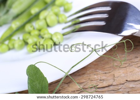 Plate, fork and peas. A branch of green peas and a plate of peas. Diet food. Low-calorie meals. Diet. A healthy diet, low-calorie food. Menu. Fork and plate. Selective focus. Raw food diet.