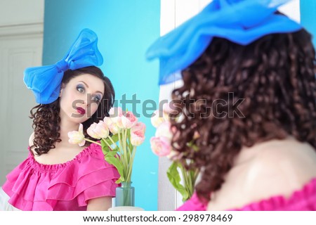 Actress playing the role of puppets in the theater. Acting, Art. Girl like a doll, a living doll. Beautiful young woman with bright makeup. Girl and tulips. A girl in a bright dress with a blue bow.
