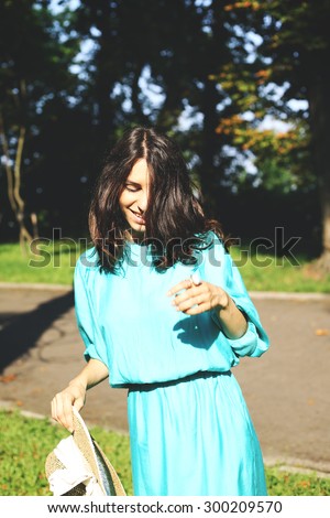 Beautiful girl in the park. Summer mood. Walk in the park. Girl in a turquoise dress. Hesitate. Experience emotions. Positive mood. Embarrassment. Shy girl. Smiling woman.