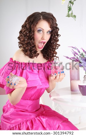 Beautiful young girl in doll look. The girl behind the desk. Surprised, scared, screaming. The girl with an open mouth. Young woman in the lush dress in the room.