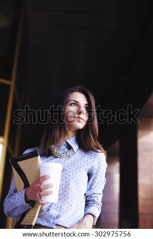 Beautiful young girl on the background of the business center. Office fashion, business fashion. Brunette. Portrait of a young woman. Office worker. Business world. Confident girl.