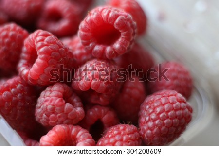 Ripe raspberries in a bowl.  Fragrant berries on the table. Background, texture. Macro picture of raspberry. Berries close-up. Juicy berries. Toned image. Selective focus.
