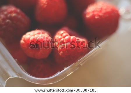 Ripe raspberries in a bowl.  Fragrant berries on the table. Background, texture. Macro picture of raspberry. Berries close-up. Juicy berries. Toned image. Selective focus.