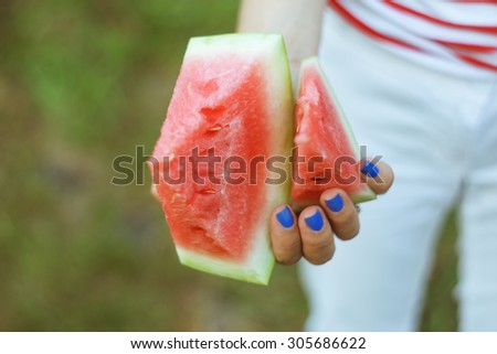 Chunks of watermelon in hands. Keep in hand. Food, diet, diet food. Girl with  blue nails. Pieces of ripe juicy watermelon. Watermelon in hand. Selective focus. Toned image.
