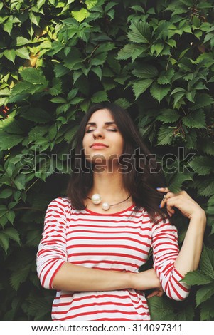 Young woman in the park. Inspiration. Woman with eyes closed. Low key. Breathing, relaxation, atmosphere. Summer mood. Wild grapes. The girl with dark hair.