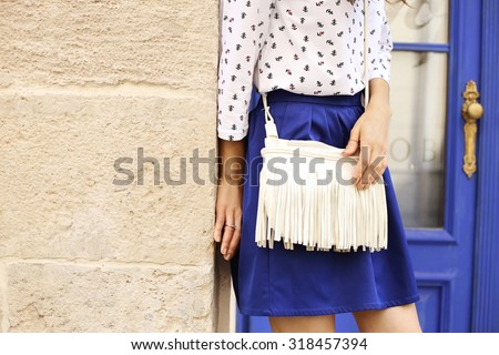 Slim tanned girl in clothes in a marine style. Marine style of dress. White bag with fringe. Indigo blue. Saturated blue. Street fashion. Fashion model. Fashion street look. Items of clothing.