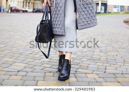 Black ankle boots, dark blue bag, a warm coat and a knitted dress. Stylish and fashionable girl on a walk. Outerwear, warm clothing. Fashionista. Clothes elements. Autumn clothes. Winter clothes.
