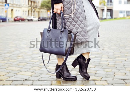 Black ankle boots, dark blue bag, a warm coat and a knitted dress. Stylish and fashionable girl on a walk. Outerwear, warm clothing. Fashionista.