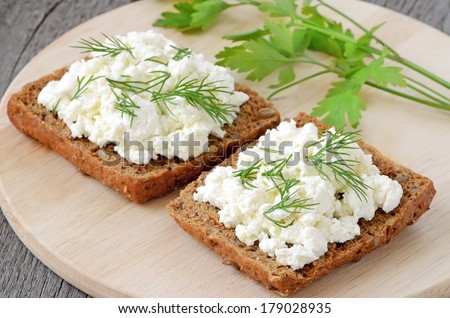Sandwiches with curd cheese and dill on cutting board