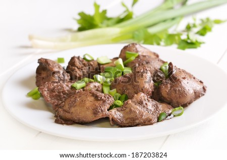 Cooked chicken liver with green onion on white plate