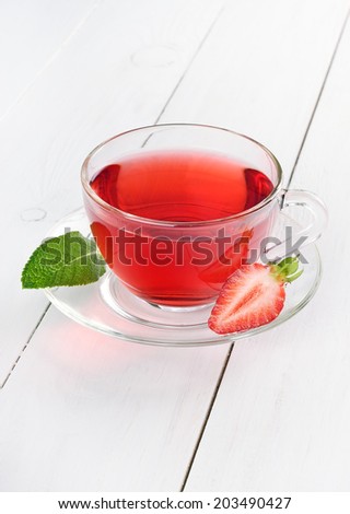 Cup of strawberry tea on white wooden table