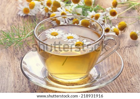 Herbal tea with chamomile flowers on rustic wooden surface