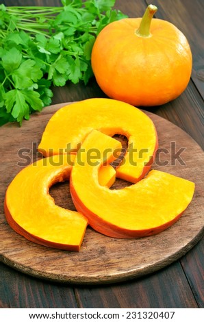 Sliced raw pumpkin on wooden cutting board on kitchen table
