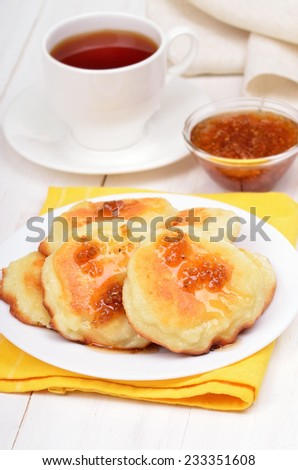 Sweet cheese pancakes, confiture and tea cup on white wooden table