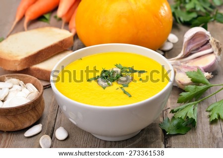 Cream soup with pumpkin, fresh vegetables and toast bread on wooden table