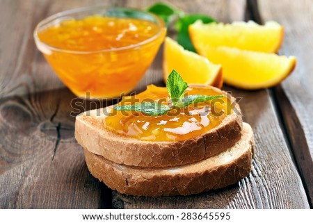 Bread and orange homemade jam on wooden table, close up view