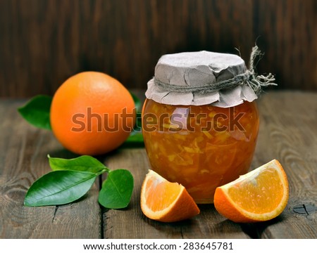 Homemade orange jam in glass jar on wooden table