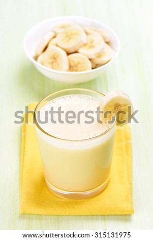 Milk cocktail with banana in glass on yellow napkin