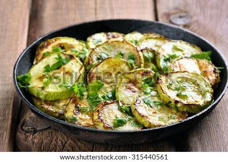 Fried zucchini with herbs in pan, close up view, shallow depth of field