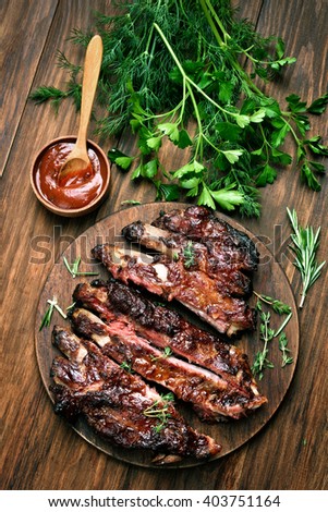 Grilled sliced barbecue pork ribs on wooden background, top view