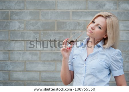 Woman thinks about something with sunglasses on the background of wall
