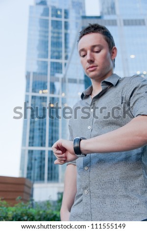 Man checking the time on the background of office buildings