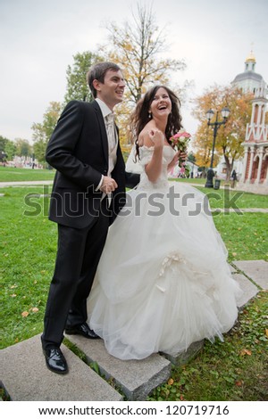 Handsome bride and funny groom stands in the park